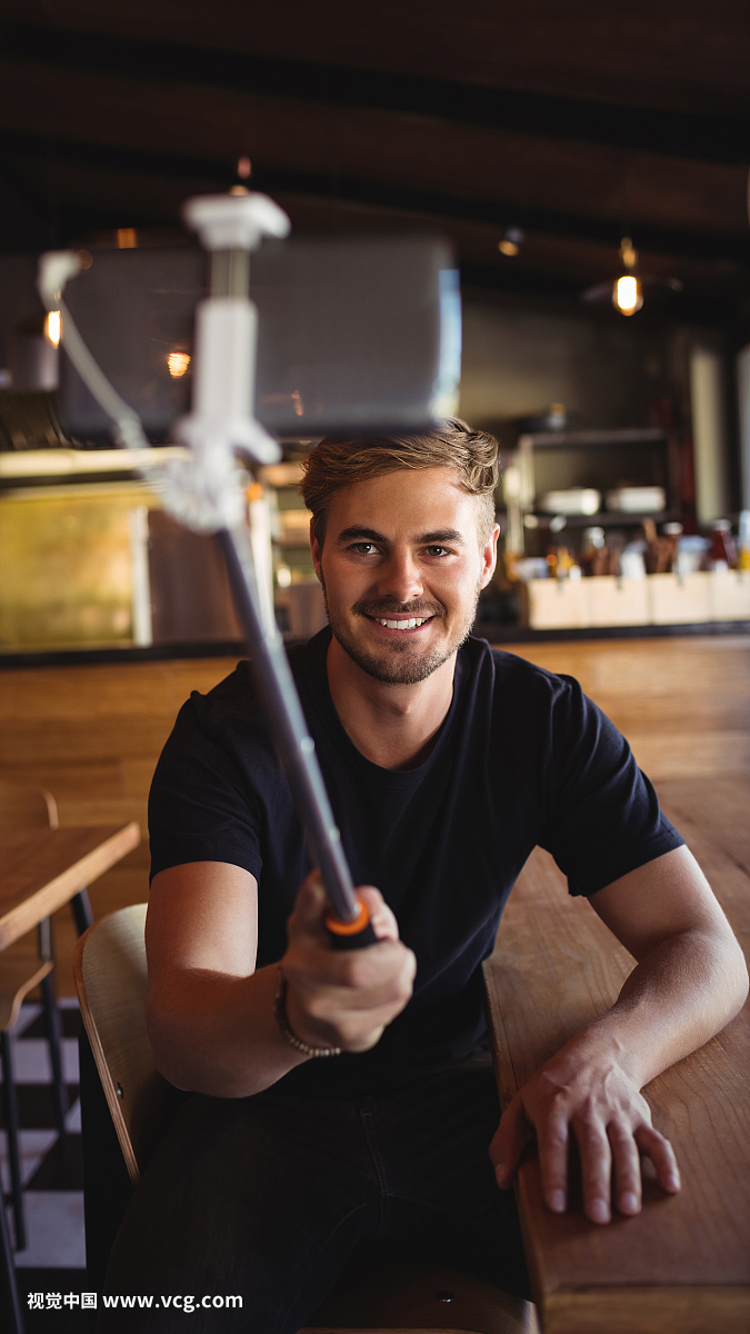 Happy man taking selfie from mobile phone in restaurant