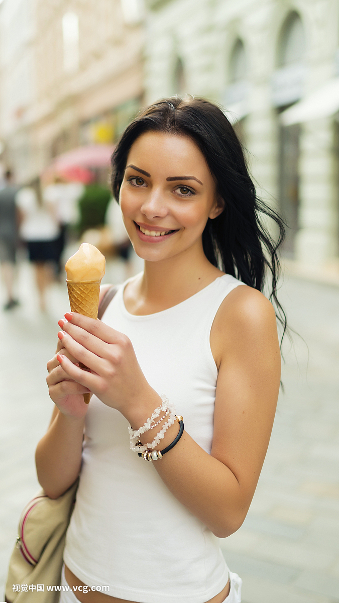在夏天城市的街道上的冰淇淋的美丽的女孩