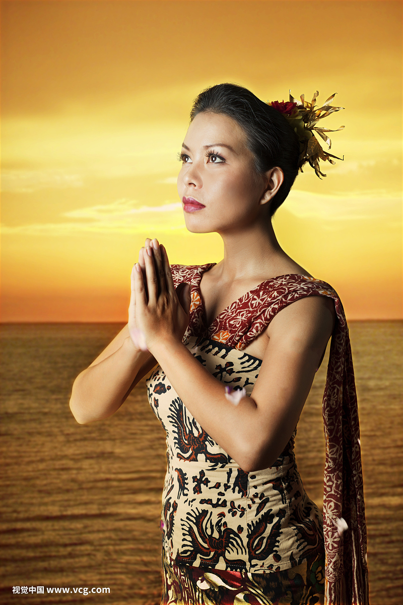 美丽的巴厘岛妇女站在日落