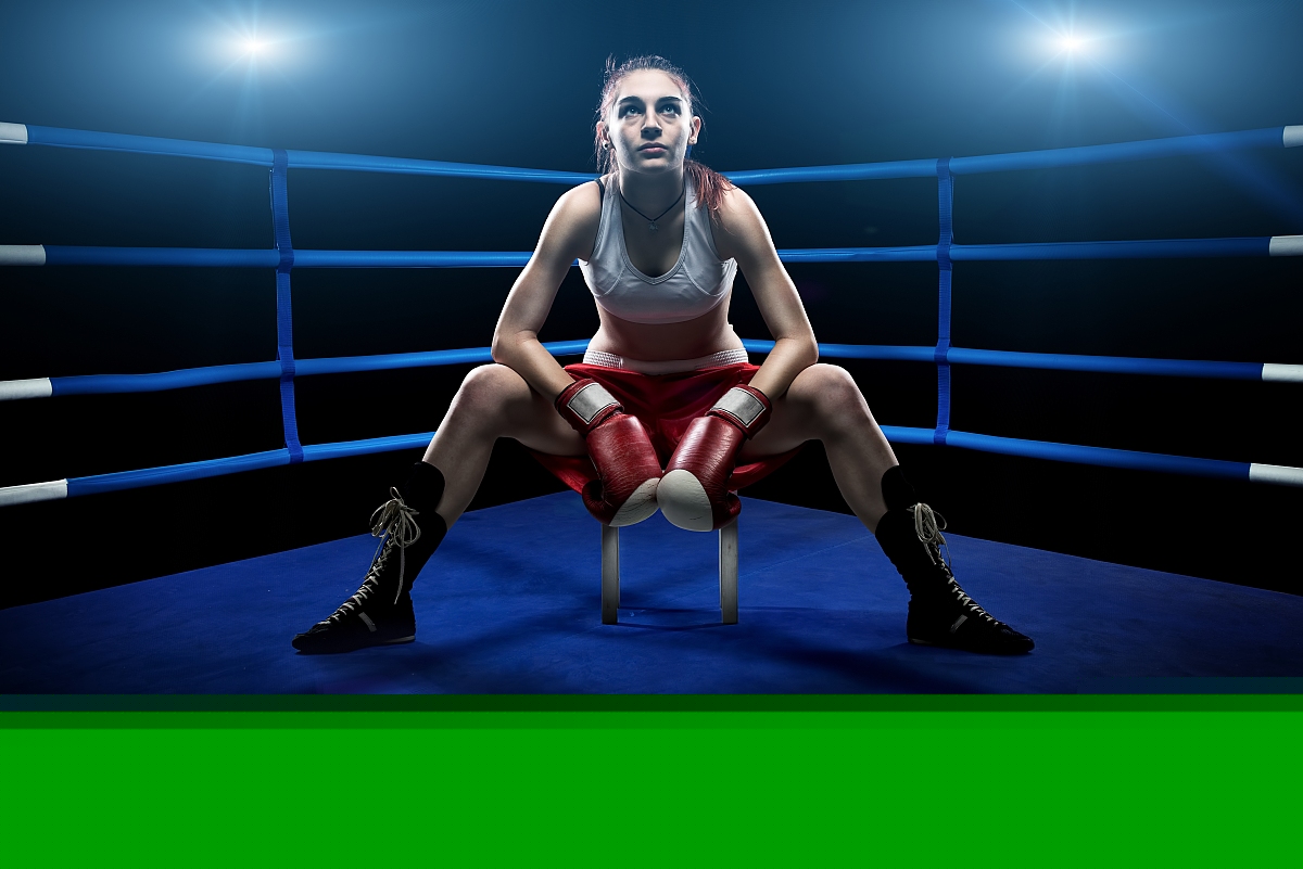 Boxing woman sitting alone in the boxing arena , surrounded by blue lights