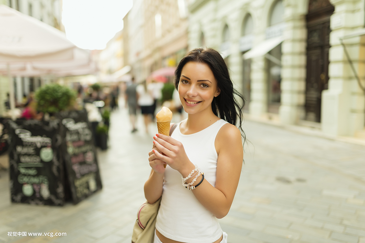 在夏天城市的街道上的冰淇淋的美丽的女孩