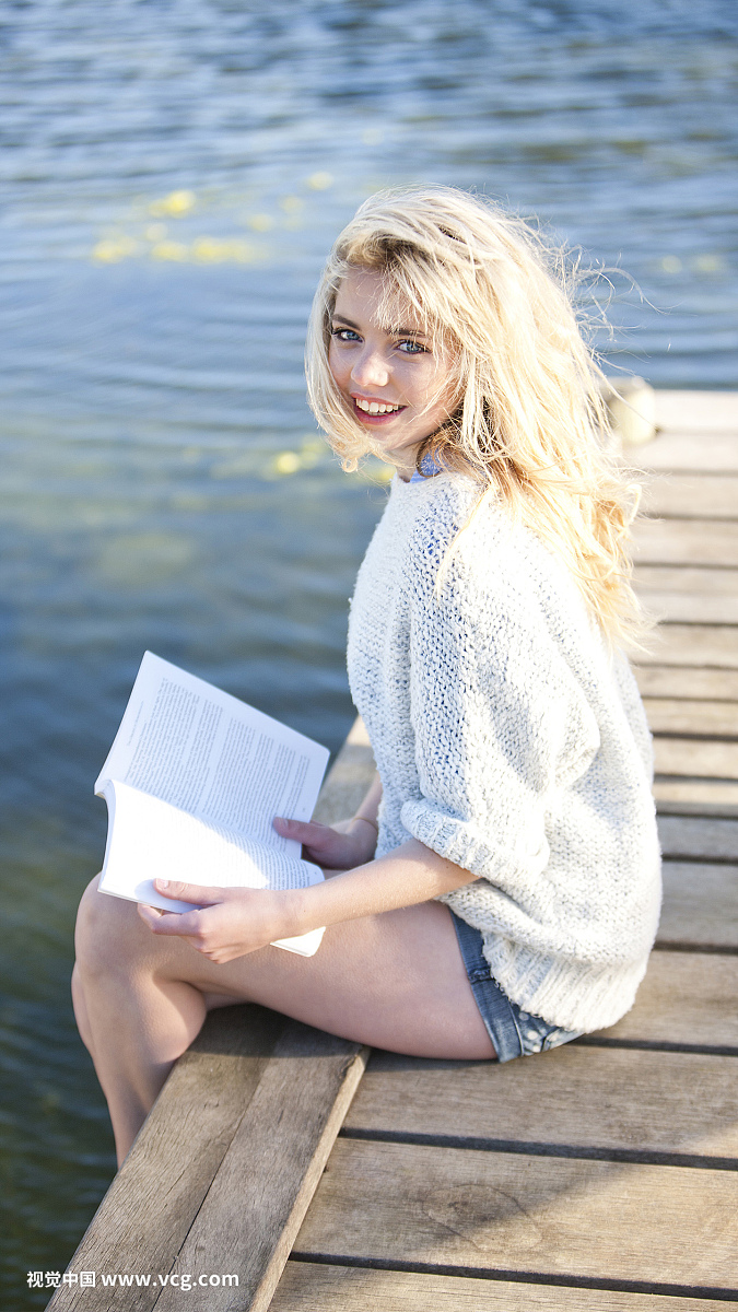 坐在码头上的年轻女子拿着书
