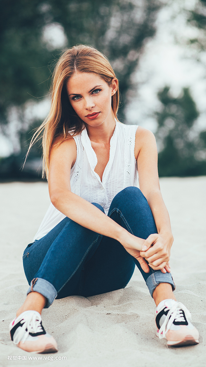 Young woman sitting on the beach sand and posing