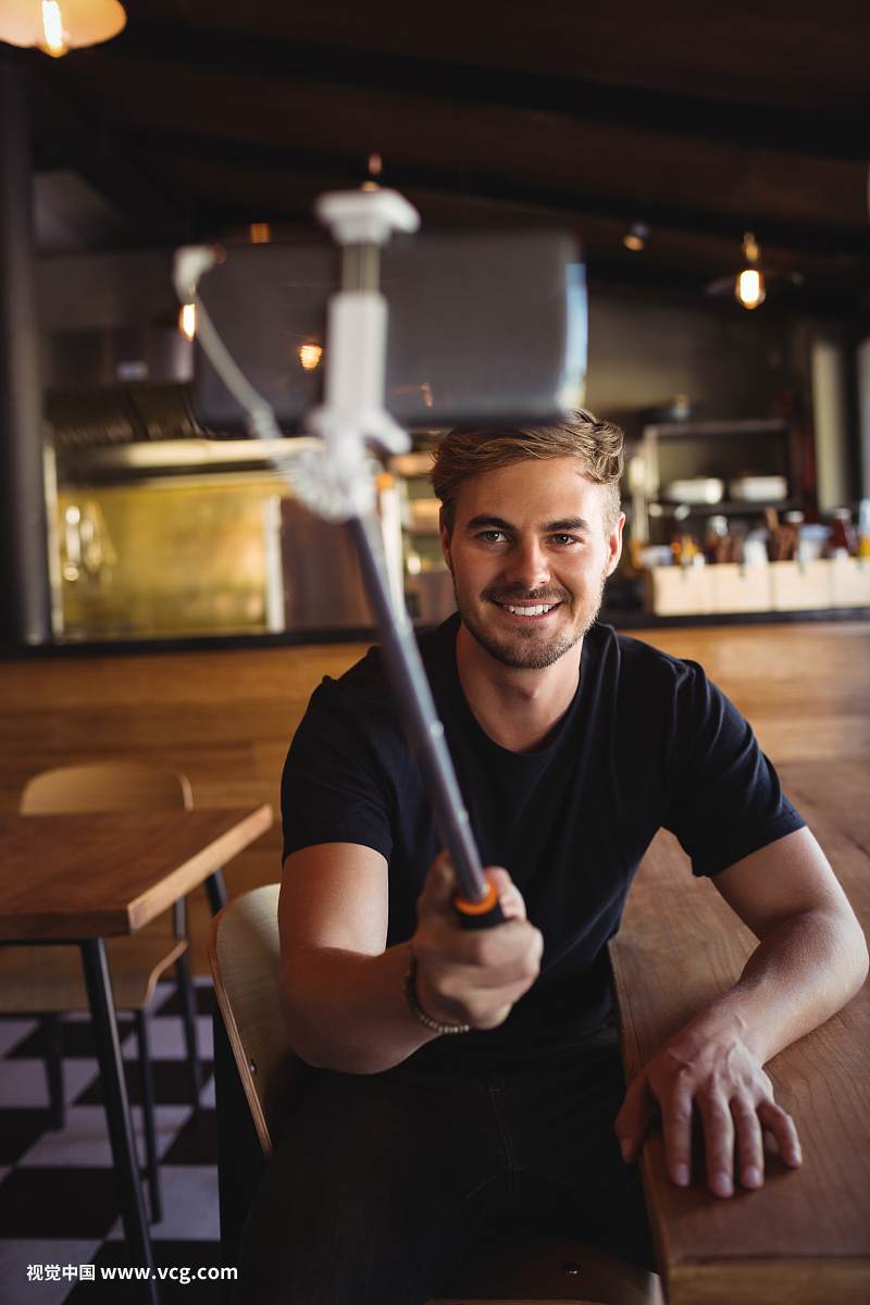 Happy man taking selfie from mobile phone in restaurant