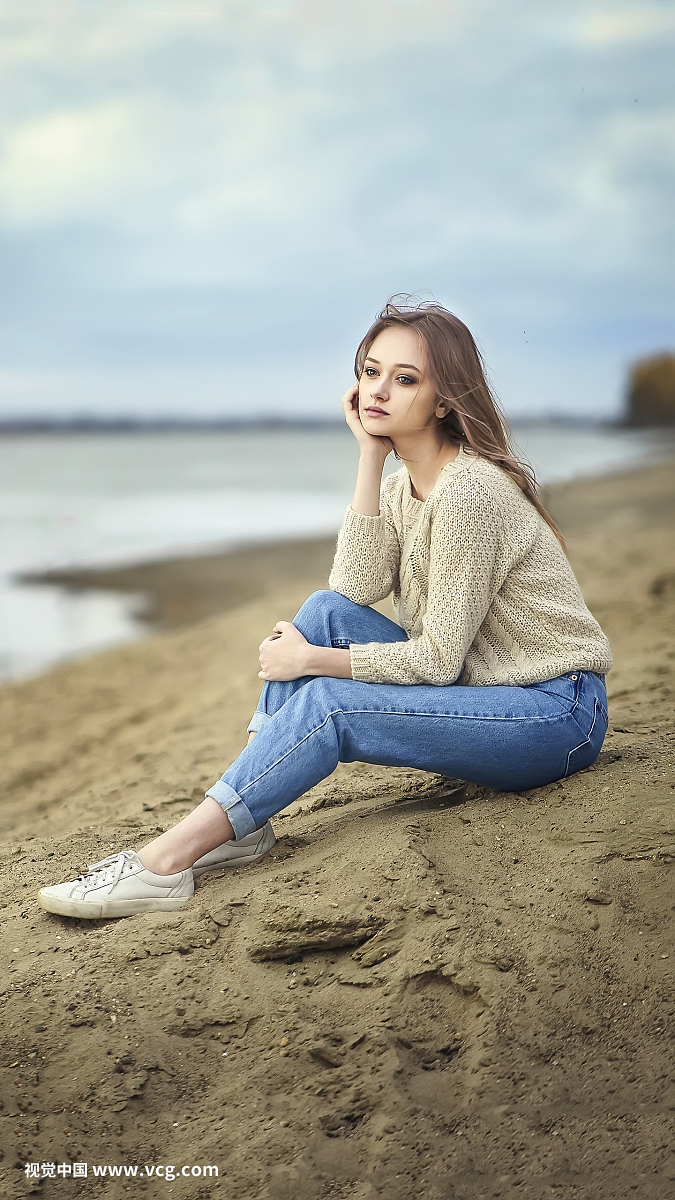 沉思的女人坐在海滩上