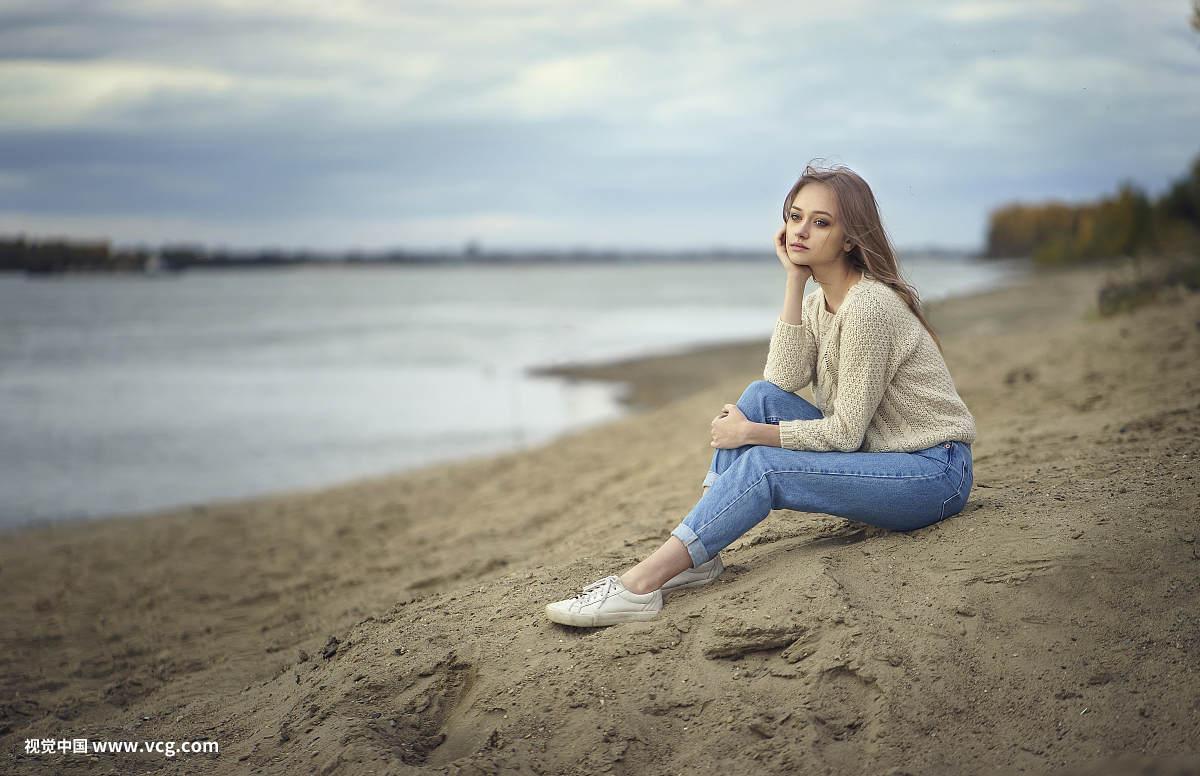 沉思的女人坐在海滩上